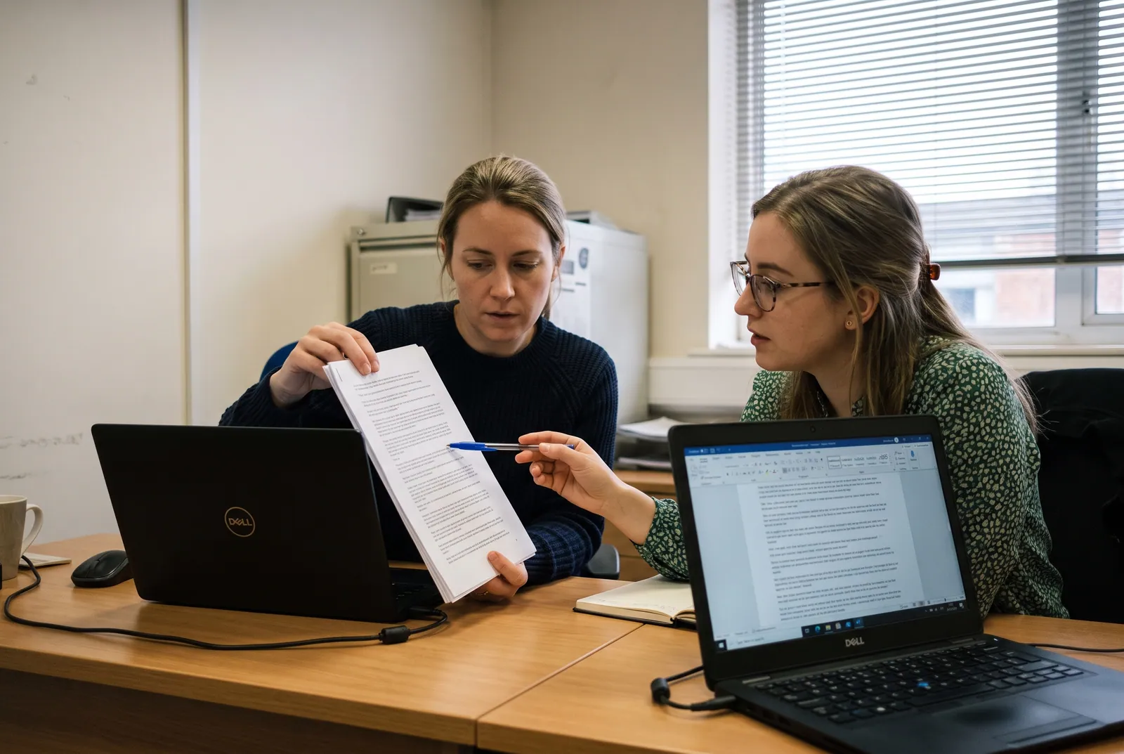 Two reviewers checking a printed transcript against the screen